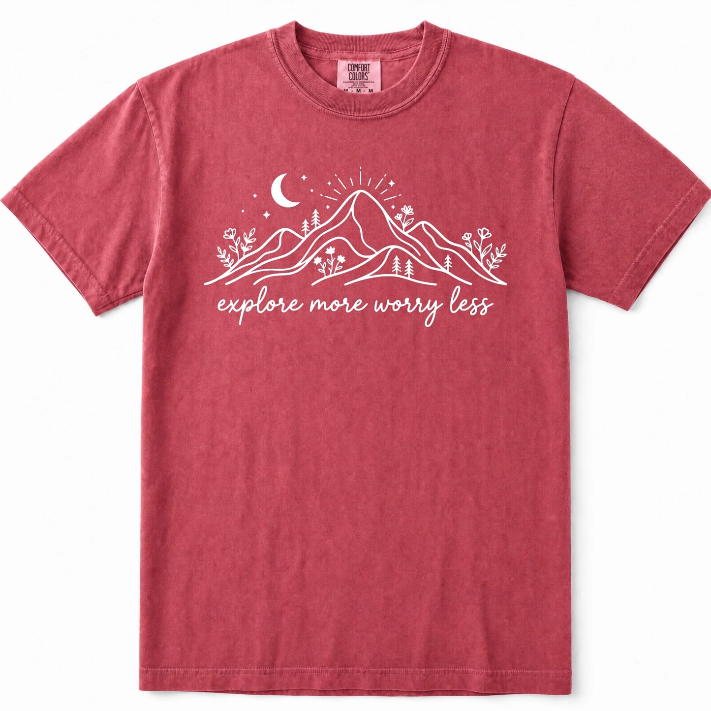 Crimson short-sleeve crewneck t-shirt in a washed, heathered red color, featuring a white graphic of mountains, a crescent moon, stars, and the text 'explore more worry less' printed across the chest.