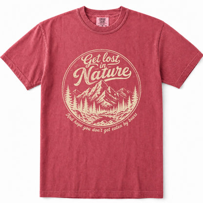Crimson short-sleeve crewneck t-shirt in a washed, heathered red color, featuring a circular vintage-style graphic on the chest with a mountain and pine tree illustration and the text 'Get lost in Nature' and 'And hope you don't get eaten by bears'.
