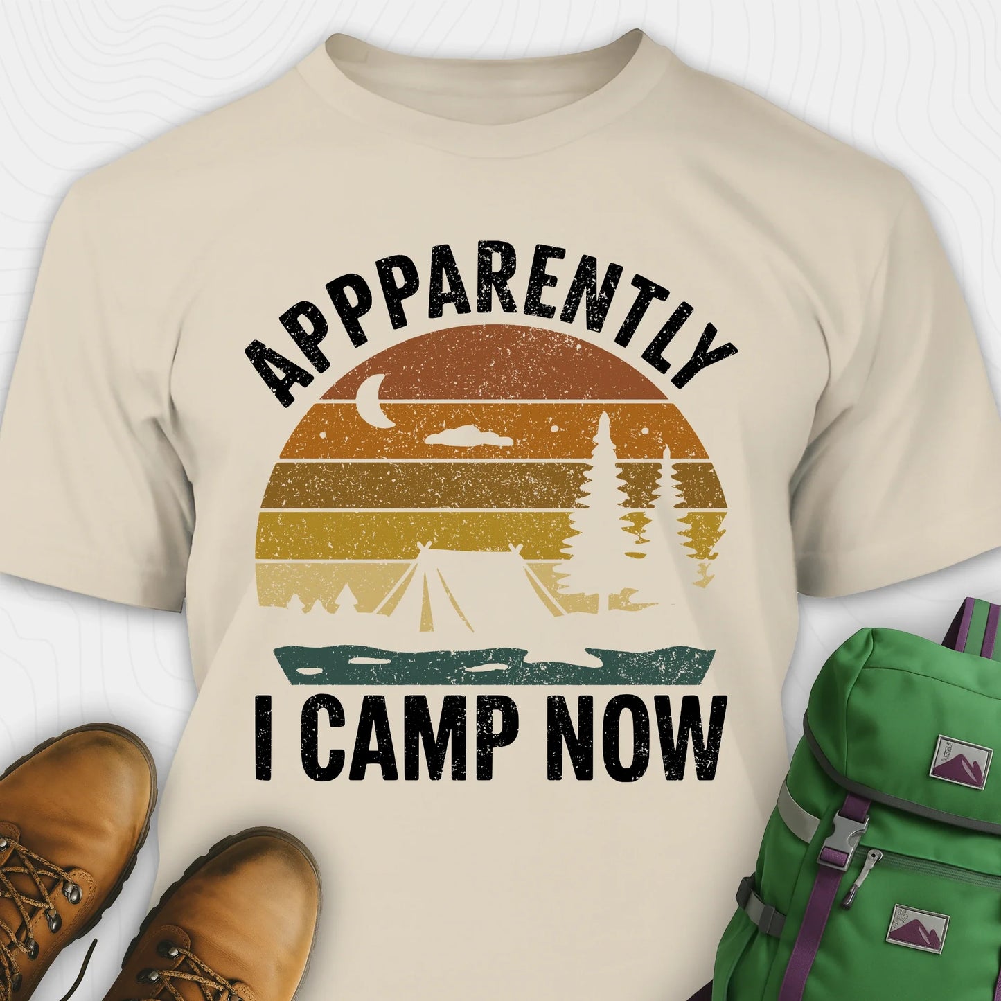 Sand t-shirt with “Apparently I Camp Now” in white text and a vintage sunset camping scene with tent, trees, and moon.
