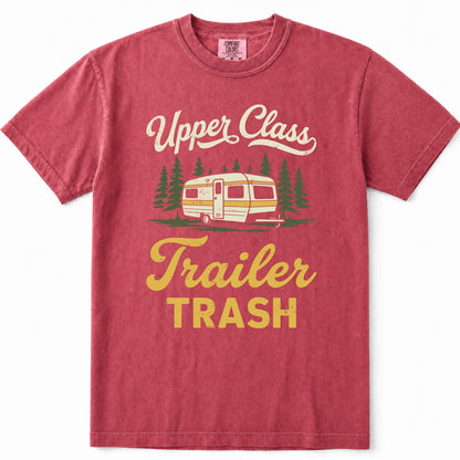 Crimson short-sleeve t-shirt with a vintage-style graphic that reads 'Upper Class Trailer TRASH' in cream and yellow lettering, featuring an illustration of a retro camper trailer and pine trees.