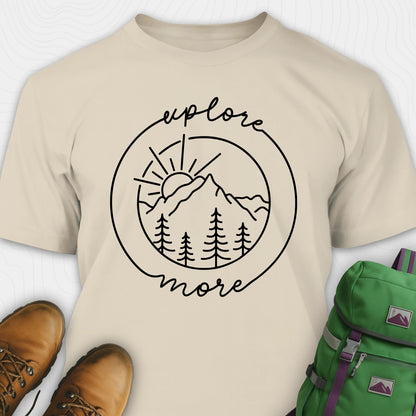 Sand explorer shirt with 'explore more' graphic design, brown boots, and green backpack on a white background