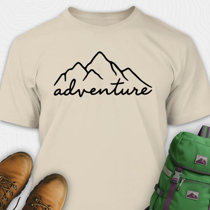 Sand adventure shirt with mountain design and 'adventure' text, paired with brown boots and a green backpack.