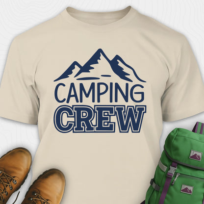 Natural camping crew t-shirt with 'Camping Crew' text and mountain graphic, paired with hiking boots and a green backpack.