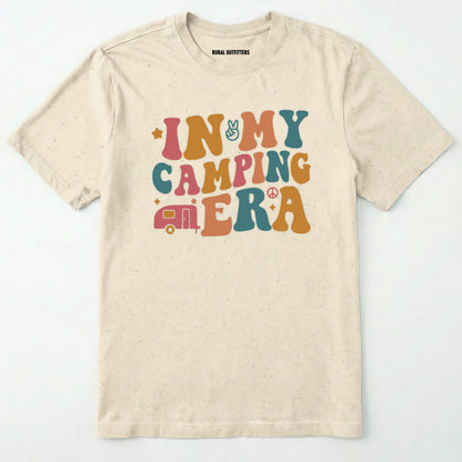 Natural cute camping shirt with colorful retro ⊜in my camping era⊝ graphic on a white background.