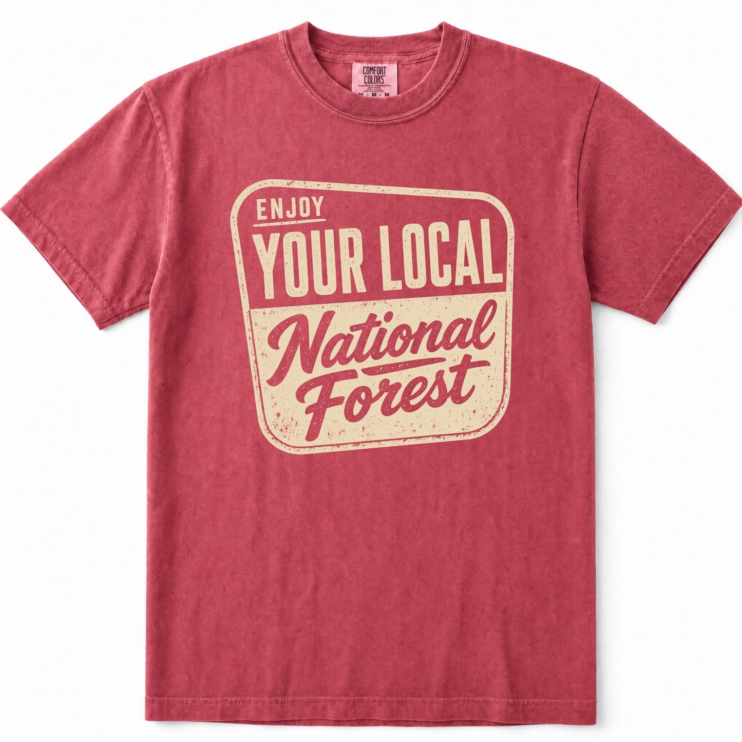 Crimson short-sleeve crewneck t-shirt in a washed, heathered red color, featuring a distressed cream-colored graphic on the front that reads 'ENJOY YOUR LOCAL National Forest'.