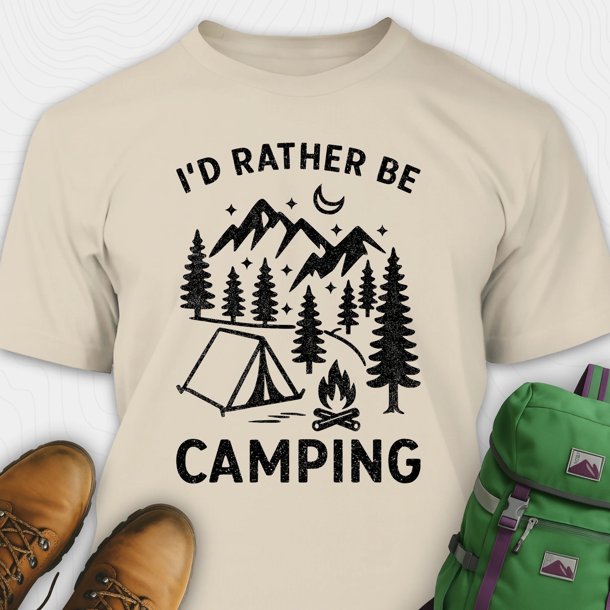 Beige t-shirt with camping graphic and text, paired with brown boots and a green backpack.