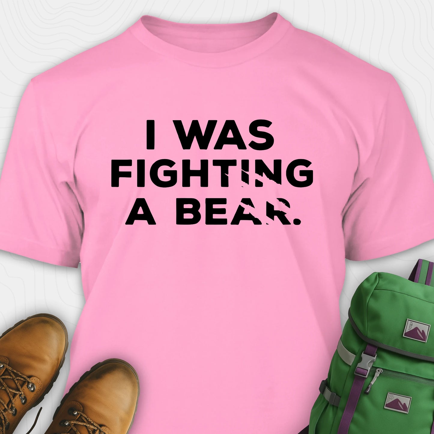 Pink I was fighting a bear shirt with a bear scratch mark graphic, paired with brown boots and a green backpack on a white background.