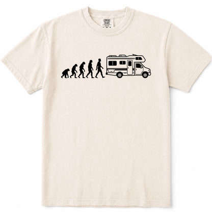 Ivory crewneck t-shirt featuring a black graphic print of the evolution of man transforming into a woman, who then drives a white and black camper RV. The shirt is displayed flat against a clean white background.