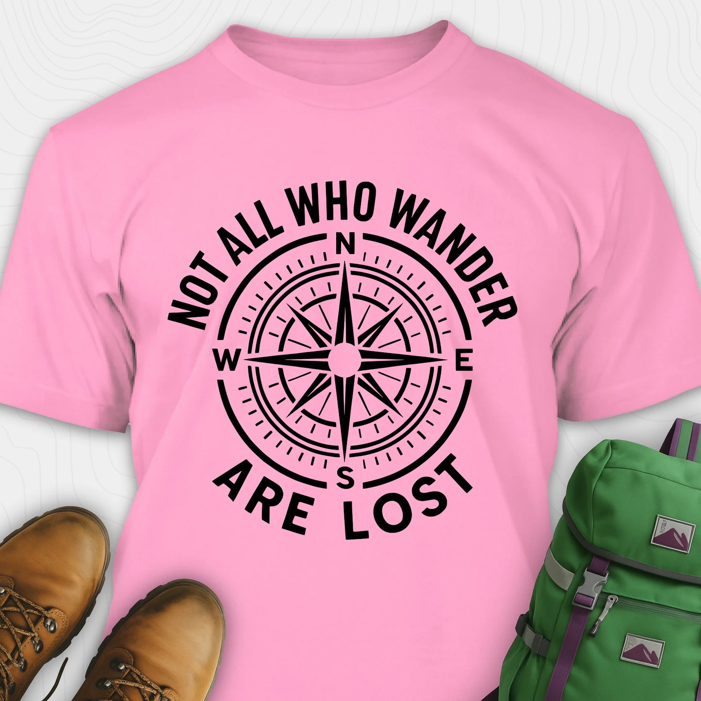 Azalea Not All Who Wander Are Lost T-shirt with compass design and text, paired with boots and a backpack on a white background