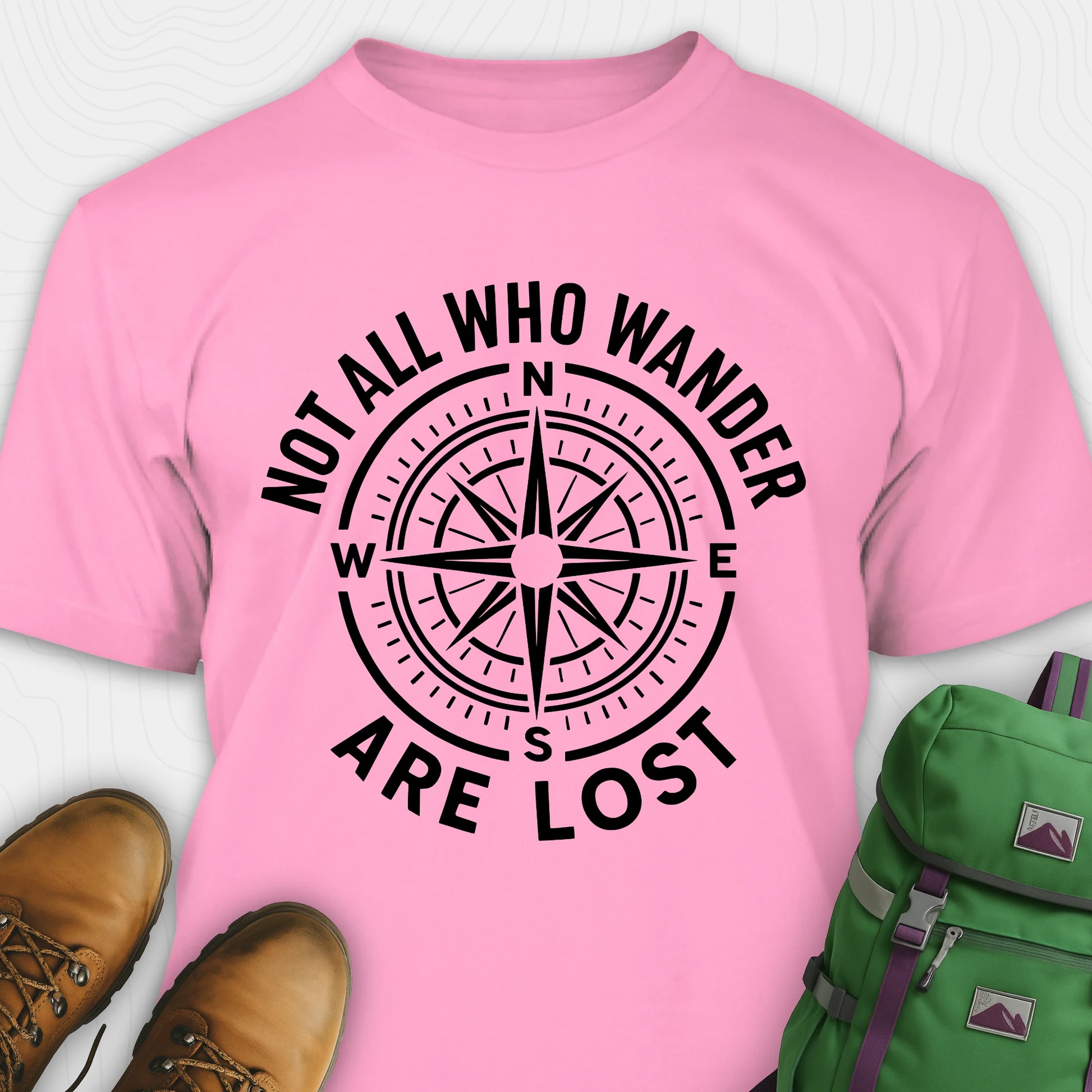 Azalea Not All Who Wander Are Lost T-shirt with compass design and text, paired with boots and a backpack on a white background