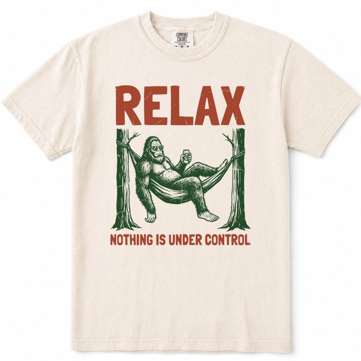 Ivory crewneck t-shirt featuring a vintage-style graphic of Bigfoot lounging in a hammock with the text 'RELAX' above and 'NOTHING IS UNDER CONTROL' below in red.