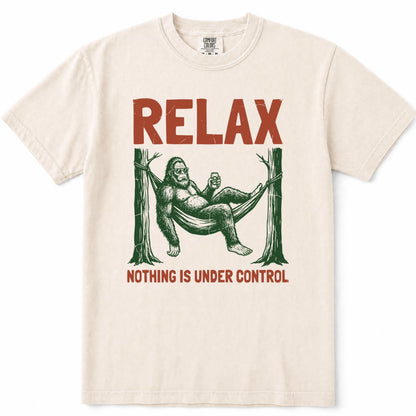 Ivory crewneck t-shirt featuring a vintage-style graphic of Bigfoot lounging in a hammock with the text 'RELAX' above and 'NOTHING IS UNDER CONTROL' below in red.