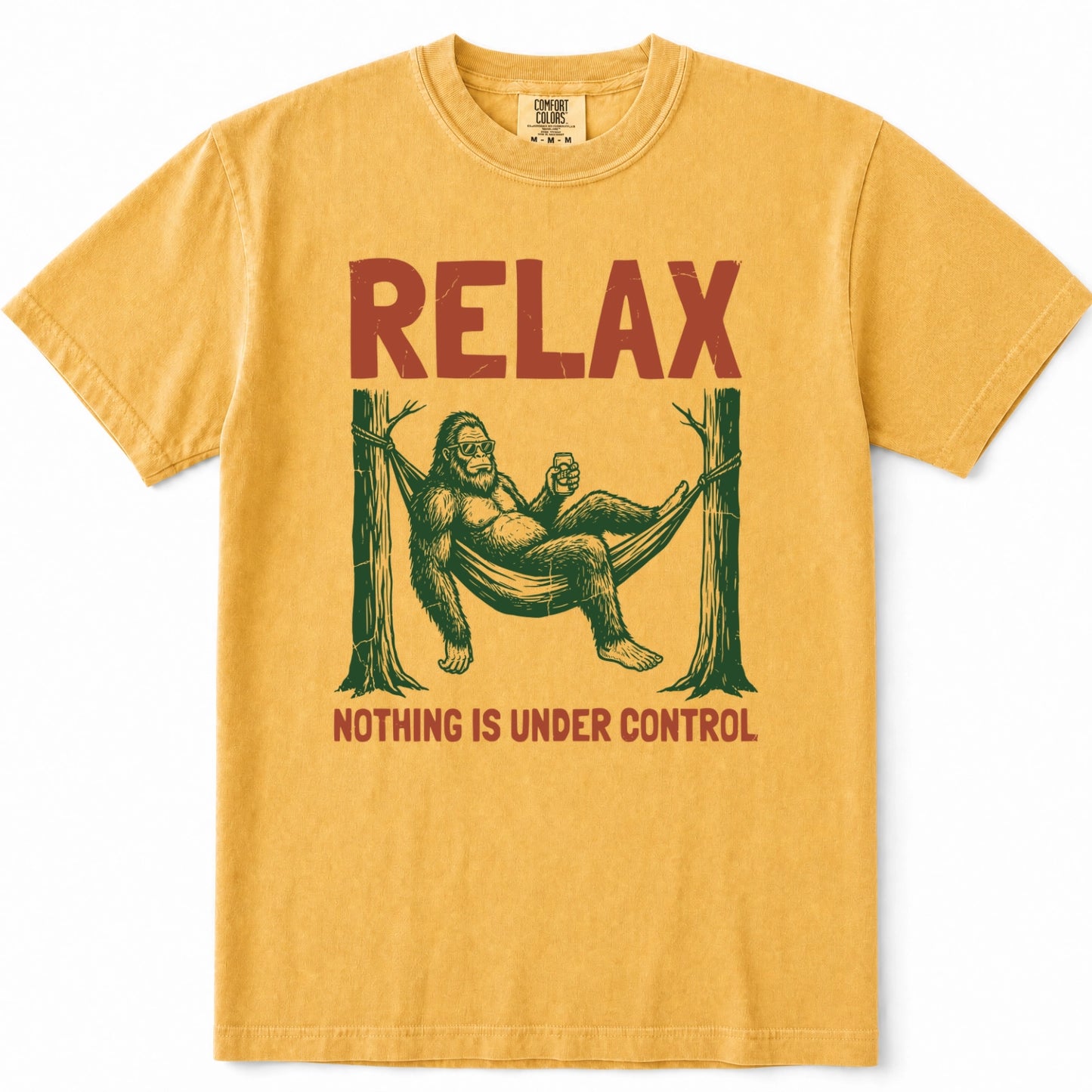 Mustard short-sleeve crewneck t-shirt featuring a retro graphic of Bigfoot lounging in a hammock with the text 'RELAX' above and 'NOTHING IS UNDER CONTROL' below.