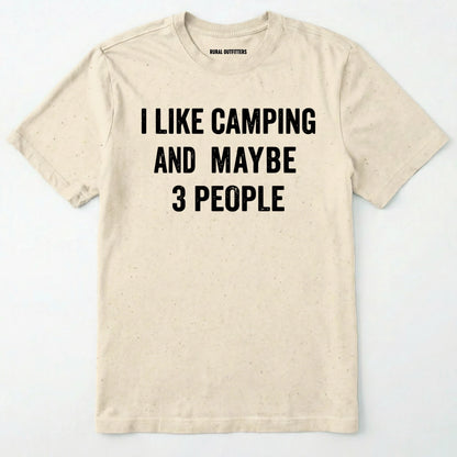 Natural short-sleeve t-shirt with bold black text reading 'I LIKE CAMPING AND MAYBE 3 PEOPLE' across the chest, laid flat against a light off-white background.