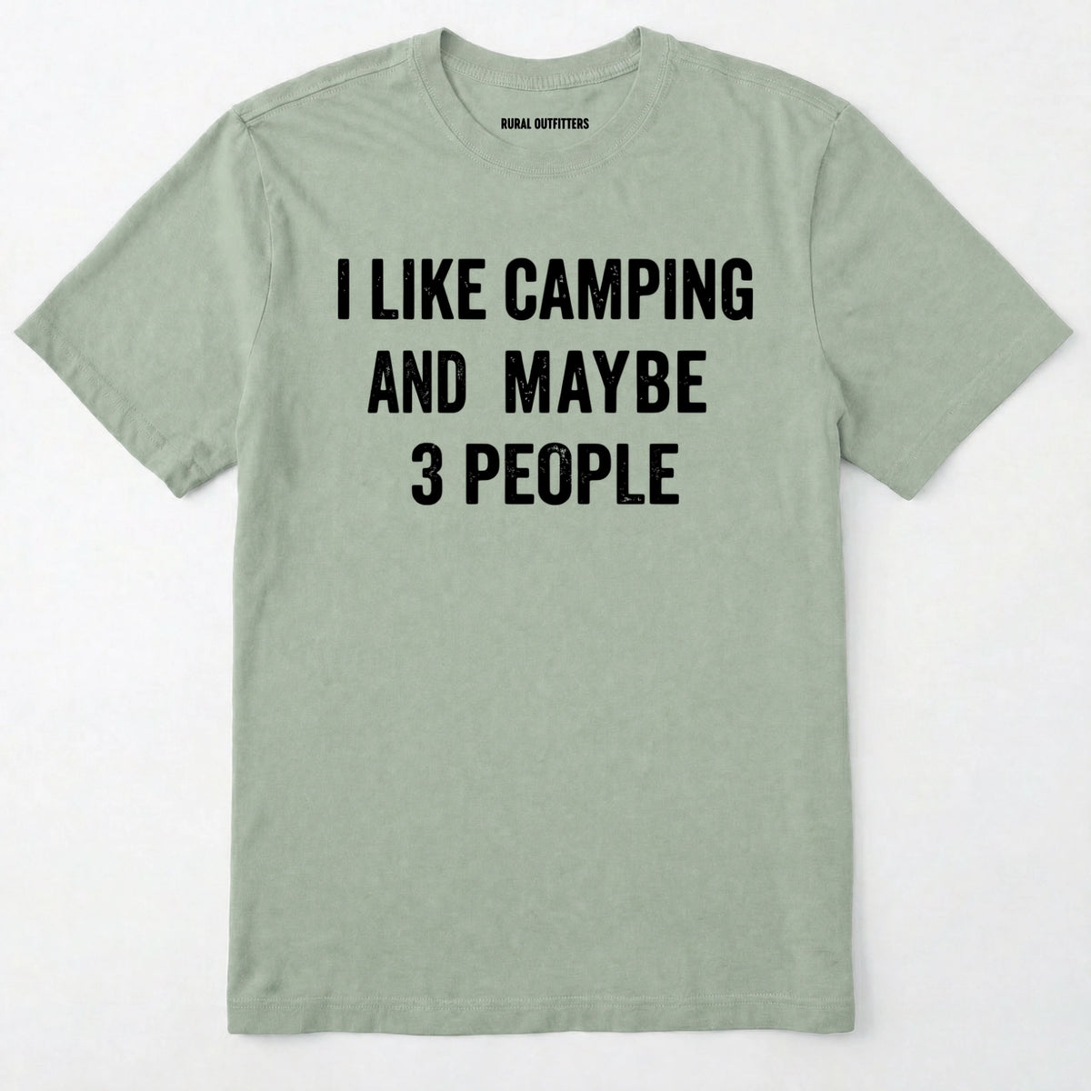 Sage short-sleeve t-shirt with bold white text reading 'I LIKE CAMPING AND MAYBE 3 PEOPLE' across the chest, laid flat against a light off-white background.