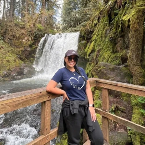Person standing on a wooden bridge with a waterfall in the background