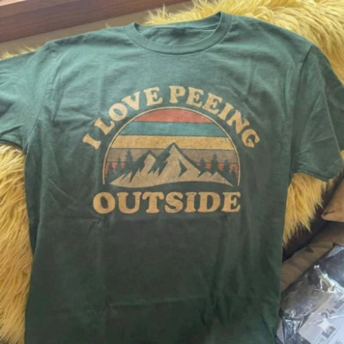 Green t-shirt with 'I Love Peeing Outside' graphic on a textured surface