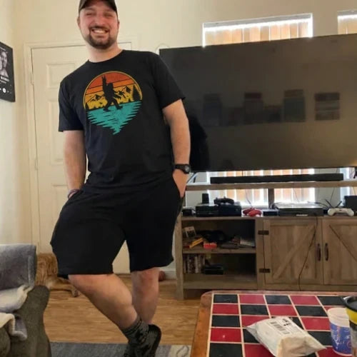 Man wearing a black t-shirt with a colorful graphic design in a living room.